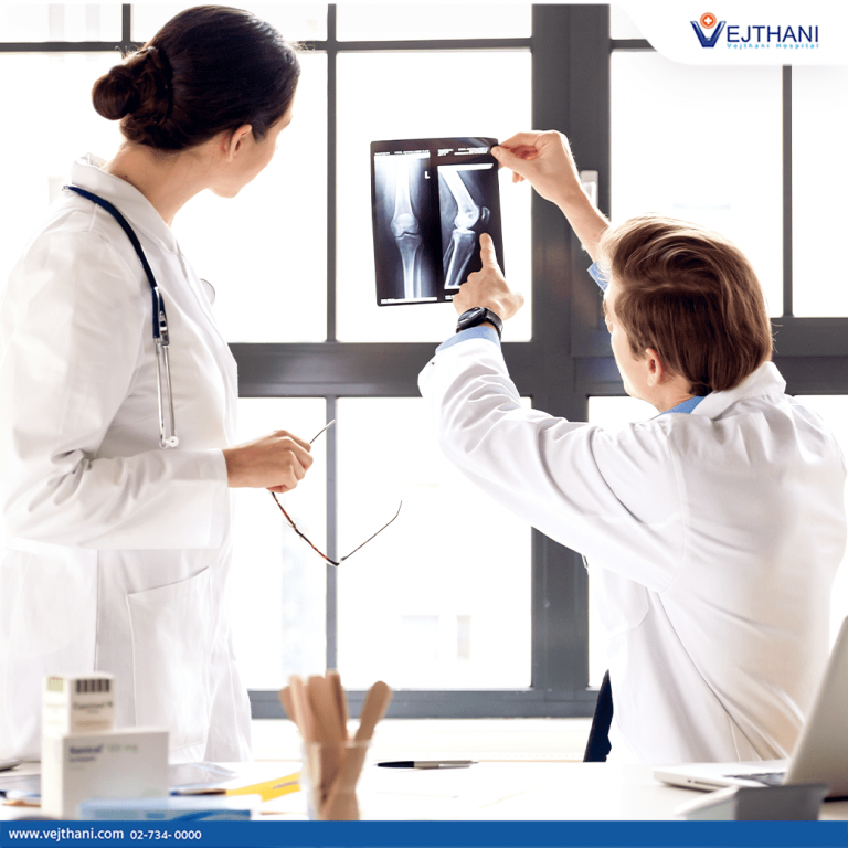 Two experienced orthopedic specialists analyze an x-ray of a knee joint.